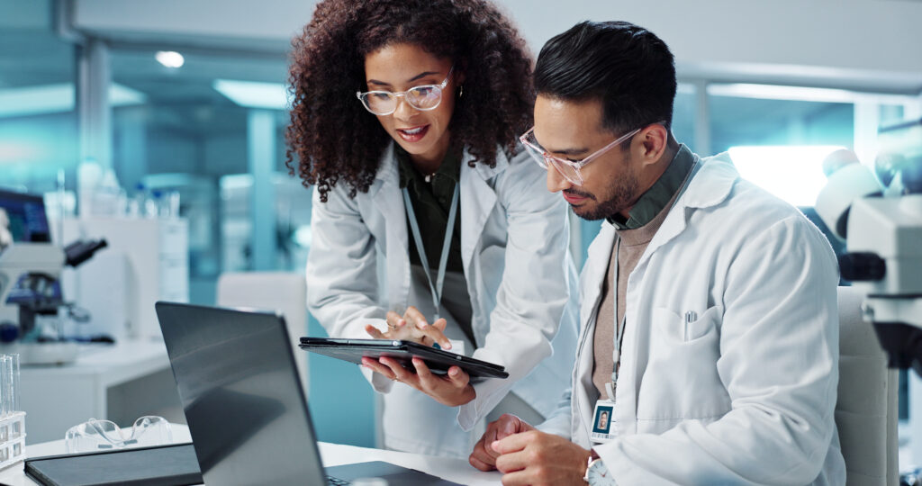 Two scientists reviewing cell therapy manufacturing data on a tablet in a laboratory, representing early supplier collaboration and regulatory planning.